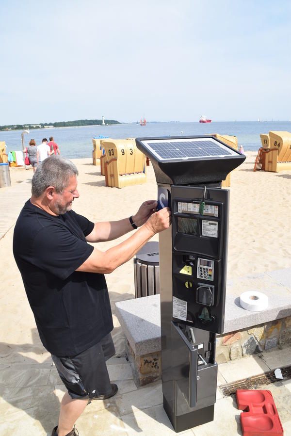 Bild vergr&ouml;&szlig;ern: Funktioniert wie ein Parkscheinautomat: Günter Schaffrath von der Firma Flowbird in Kiel bei der Montage des ersten Strandgebührenautomats am Möltenorter Strand.