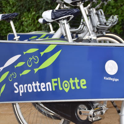Die Fahrräder der Sprottenflotte stehen an Bügeln mit auffälligem Logo. 
