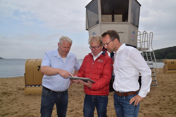 Bild vergr&ouml;&szlig;ern: Stabiles WLAN-Signal: Bürgermeister Tade Peetz (von links) , Niels Tönder von der IT-Abteilung des Amtes und FDP-Gemeindevertreter Gunnar Schulz am Strand von Möltenort.