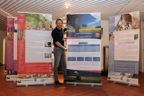 Der Klimaschutzmanager des Kreises Plön, Dr. David-Willem Poggemann, präsentiert hier die mobile Klimaschutz-Ausstellung im Foyer des Kreishauses. 
