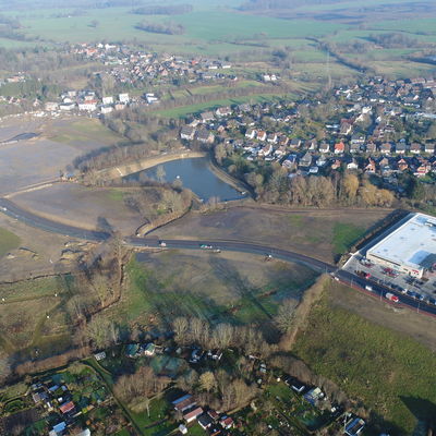 Bild vergr&ouml;&szlig;ern: Die neue innerörtliche Straße durch das erweiterte Schönkirchener Gewerbegebiet verbindet die B 502 mit der Schönberger Landstraße in Bereich des Rewe-Marktes/Med-Huus (rechts im Bild).