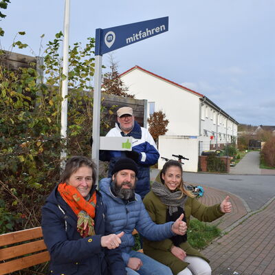 Bild vergr&ouml;&szlig;ern: Mitfahrbank Hegerade: Bürgermeisterin Hilla Mersmann, Derek Palme, Lena von Possel (KielRegion) und Peter Lehswing hinter dem ausklappbaren Mitfahr-Daumen.