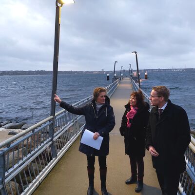 Bild vergr&ouml;&szlig;ern: Mönkebergs Bürgermeisterin Hilla Mersmann (links) mit Ministerpräsident Daniel Günther und Landrätin Stephanie Ladwig  auf dem Fähranleger.