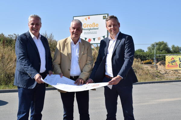 Bild vergr&ouml;&szlig;ern: Franchisee Thomas Brand (von links), Schönkirchens Bürgermeister Gerd Radisch und Christian Dust (Immobilien Mc Donald's) beim Blick auf die Planzeichnung.