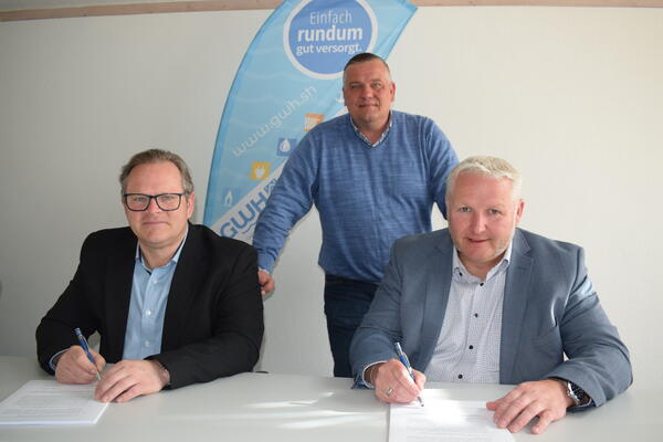 Tim Lüdemann, Vorstand der Gemeindewerke AöR, und Bürgermeister Tade Peetz bei der Vertragsunterzeichnung. Dahiner Lars Husfeld/Leiter Stromversorgung der GWH.