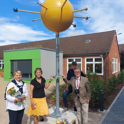 Bild vergr&ouml;&szlig;ern: Ein Planetenmodell in Stahlbauweise: Rudi Behrendt (rechts, dahinter Schulhofplaner Arne Levsen) hat das Modell entworfen und als Geschenk für die Mönkeberger Grundschule größtenteils selbst finanziert.